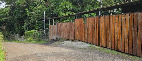 A gravel path leading to a wooden fence with a metal gate.