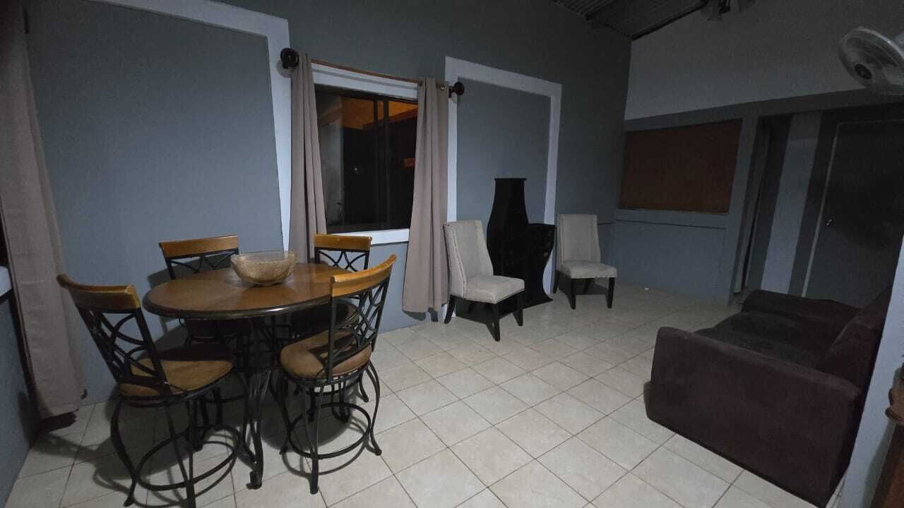 A dining area with a round table and chairs, a sofa, and a large vase.