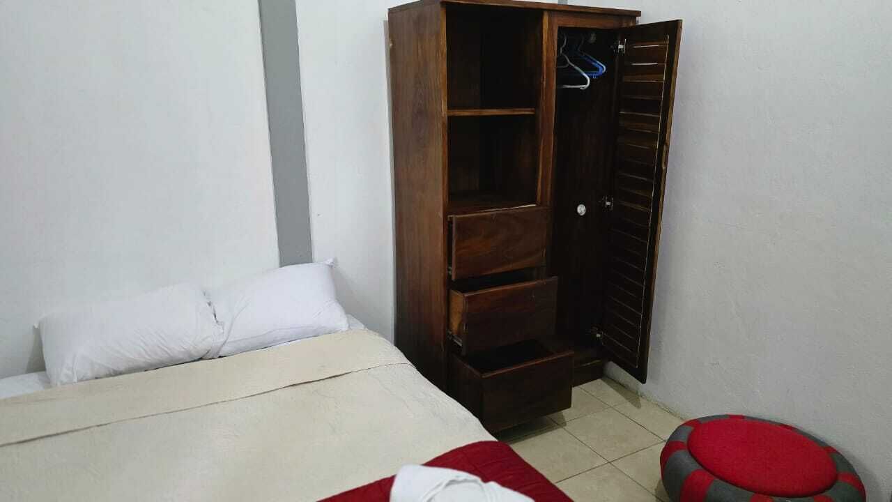 Un dormitorio con una cama, un armario y un taburete.