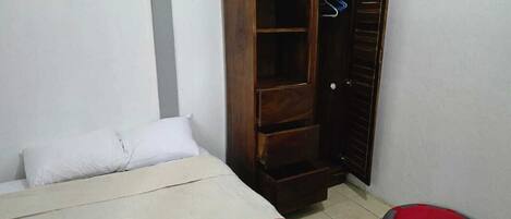 Un dormitorio con una cama, un armario y un taburete.
