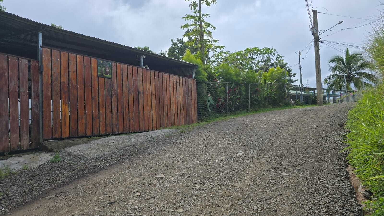 A gravel road leading to a wooden fence with a metal gate.