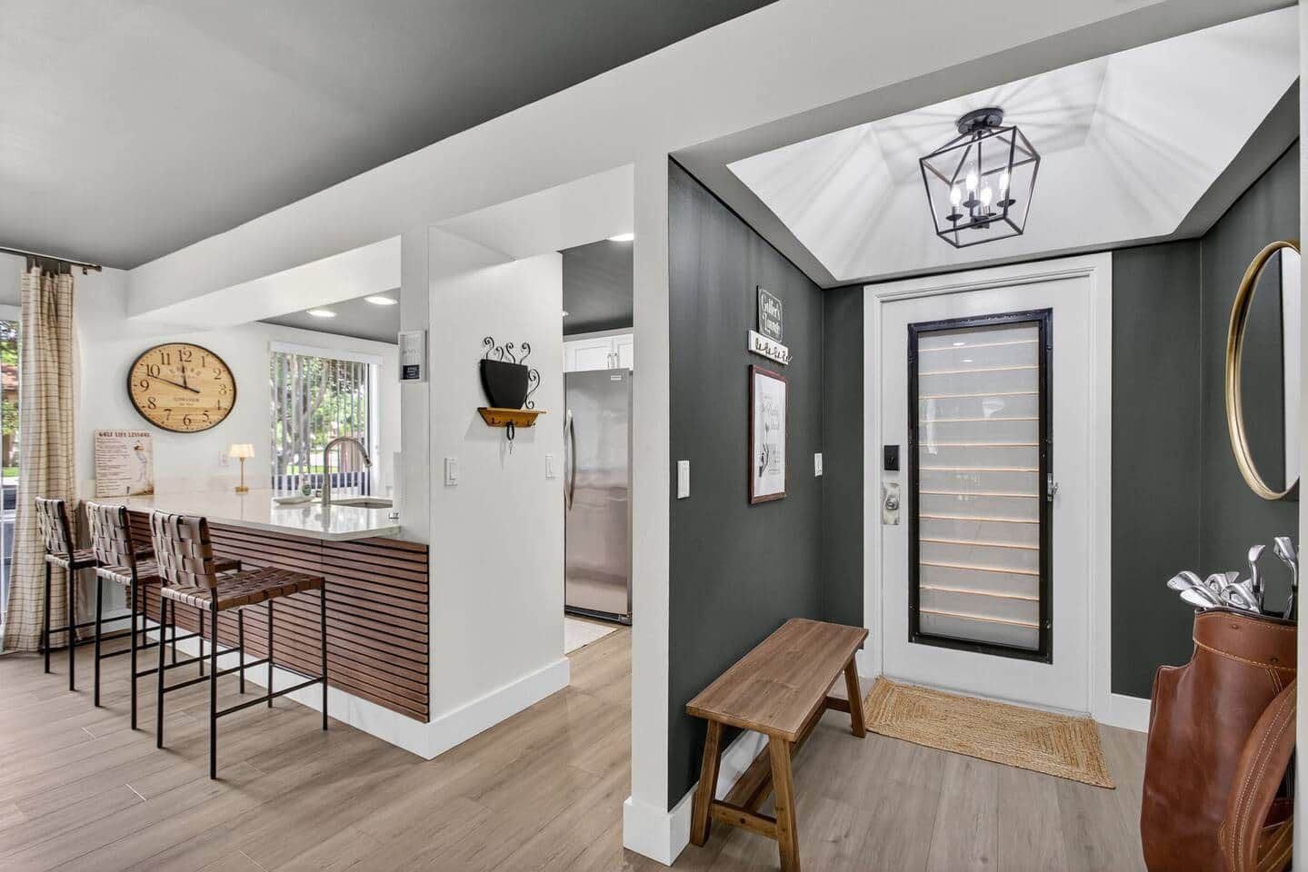 Un intérieur moderne comprenant un bar, une horloge, un réfrigérateur et un banc.