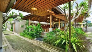A covered outdoor area with wooden beams, potted plants, and a pathway leading to a building with a bar area. - Mahayoga Ubud Private Pool Villa Spa And Resto (Bali)