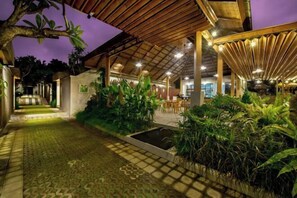 A covered outdoor area with a tiled walkway, surrounded by lush greenery and a small water feature. - Mahayoga Ubud Private Pool Villa Spa And Resto (Bali)