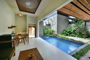A modern interior with a pool, dining area, and a view of greenery. - Mahayoga Ubud Private Pool Villa Spa And Resto (Bali)