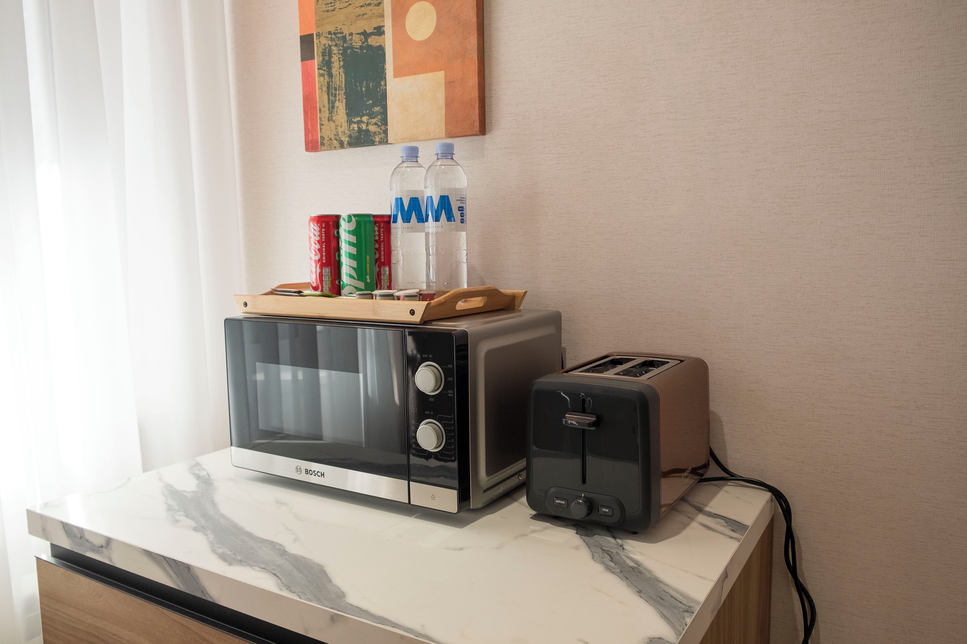 A kitchen counter with a Bosch microwave, a toaster, and two water bottles.