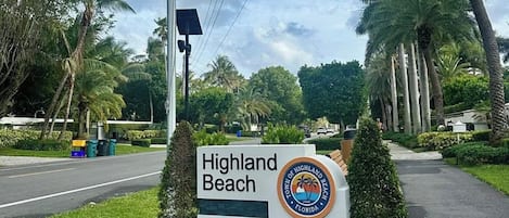 A sign for Highland Beach with a palm tree and flowers.