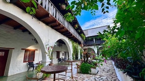 A courtyard with stone flooring, outdoor seating, and lush greenery. - GARDEN HOTEL (Copan Ruinas)
