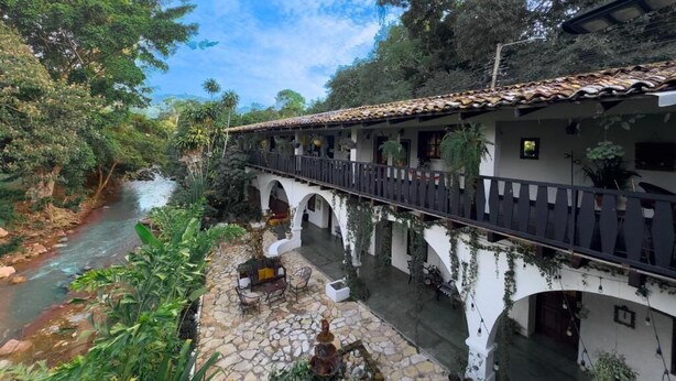 A courtyard with a river, stone flooring, and a bridge with arches. - GARDEN HOTEL (Copan Ruinas)
