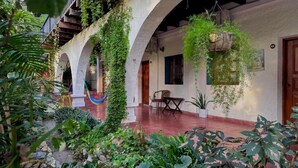 A courtyard with arches, hanging plants, and a wooden table. - GARDEN HOTEL (Copan Ruinas)