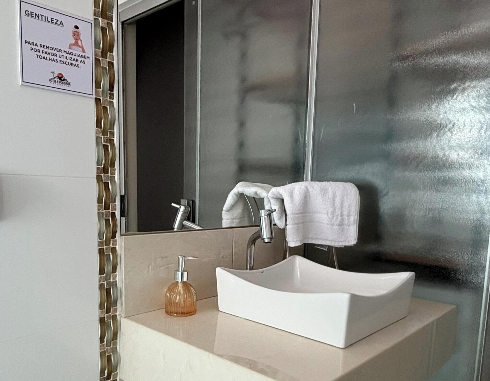 Een badkamer met een witte wastafel, een spiegel en een handdoek aan de muur.