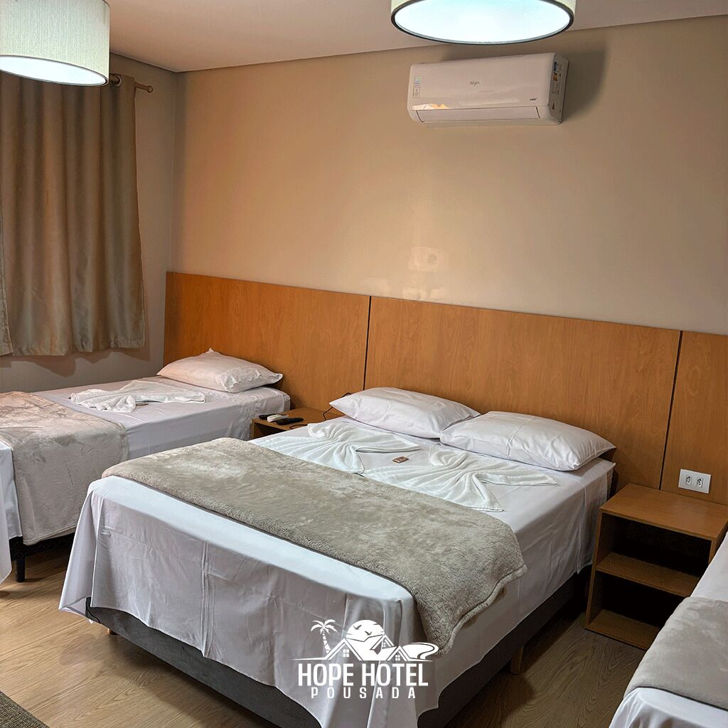 A hotel room with two beds, a wooden headboard, an air conditioning unit, and a nightstand with a lamp.