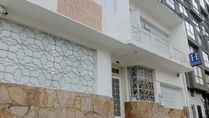 Un hotel con fachada blanca, base de piedra y un letrero azul que indica que es un hotel.