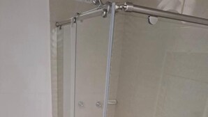 Un baño con ducha de vidrio, inodoro y lavamanos.
