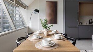A modern kitchen with grey cabinets, a wooden dining table set with white bowls and plates, and a potted plant on the table. - Resort Style Property 2B/2B walk to Everything! (Cleveland)