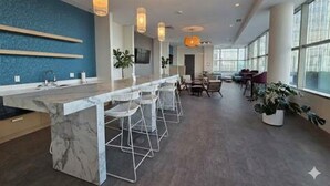 A modern kitchen with a marble island, bar stools, pendant lighting, and large windows. - Resort Style Property 2B/2B walk to Everything! (Cleveland)