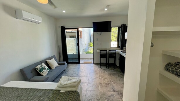 Un espacio habitable compacto con sofá, una pequeña zona de comedor y una kitchenette.