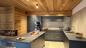 Uma cozinha moderna com ilha central, eletrodomésticos embutidos e parede de pedra decorativa.