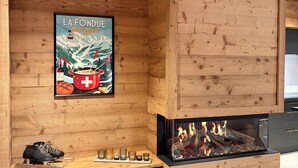 Interior de madeira com lareira, um cartaz de 'La Fonde Savoyarde' e um par de sapatos em um balcão.