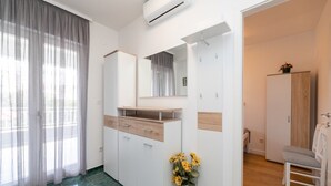 Ett modernt hotellrum med ett stort fönster, en spegel, en garderob och en stol.