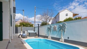 En swimmingpool med ett kaklat poolområde, ett bubbelbad och en vägg dekorerad med palmträd.