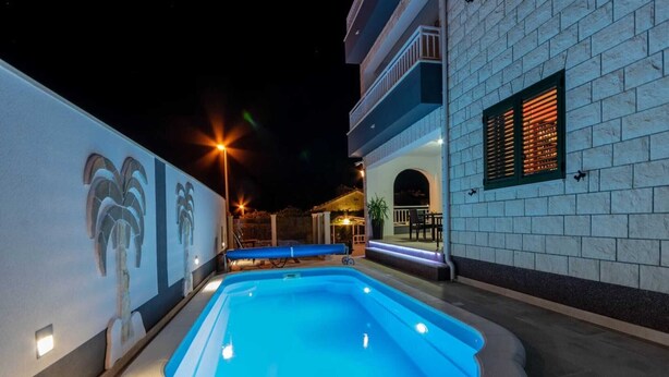 Una piscina circondata da un edificio bianco con un balcone.