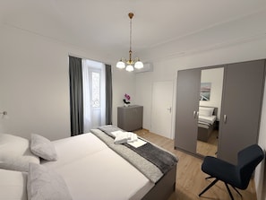 Et moderne hotelværelse med seng, skrivebord, stol, garderobe og en dør til et andet rum.