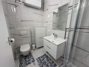 Et moderne badeværelse med toilet, håndvask og bruser.