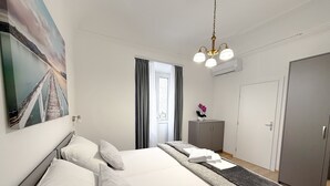 Ett modernt hotellrum med en stor säng, en garderob, ett skrivbord och en tavla på väggen.