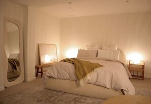Ein Schlafzimmer mit Bett, Nachttisch, Spiegel und Lampe.