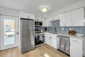 A modern kitchen with stainless steel appliances, white cabinets, and a tiled backsplash. - Cozy Coastal Retreat–1BR w/Kitchen & Ocean Access-unit 9 (New Smyrna Beach)