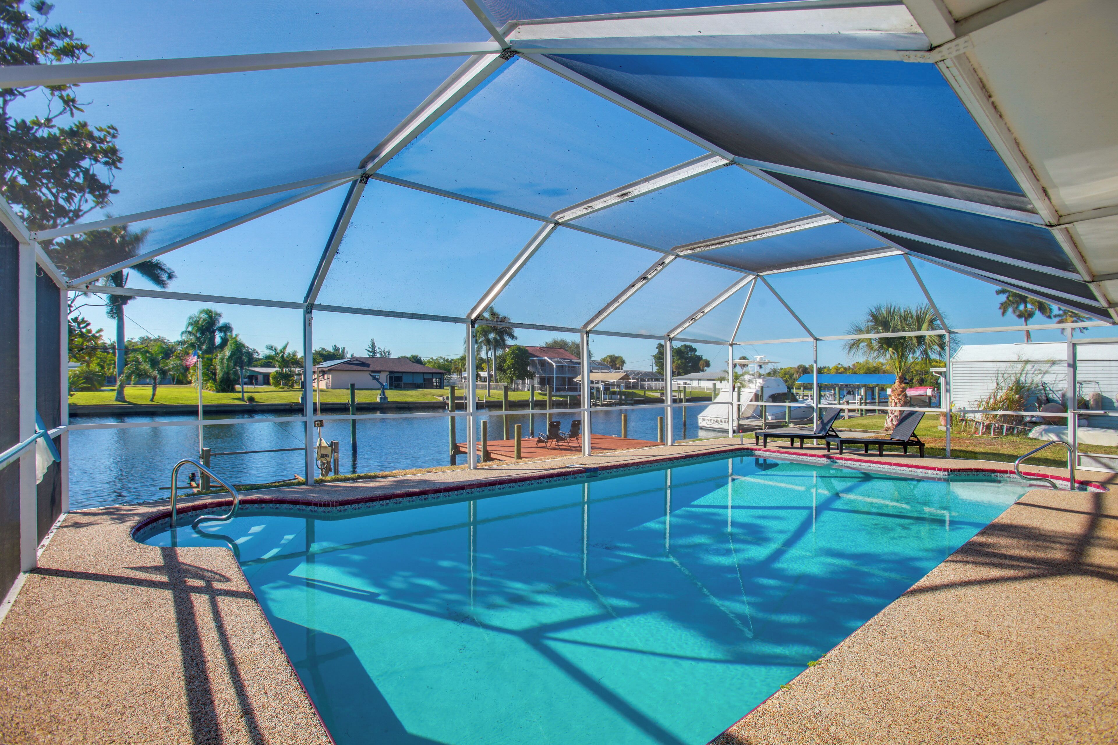 A covered swimming pool with a view of a lake and surrounding greenery.