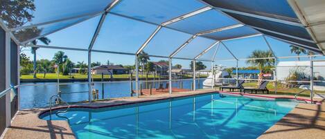 A covered swimming pool with a view of a lake and surrounding greenery.