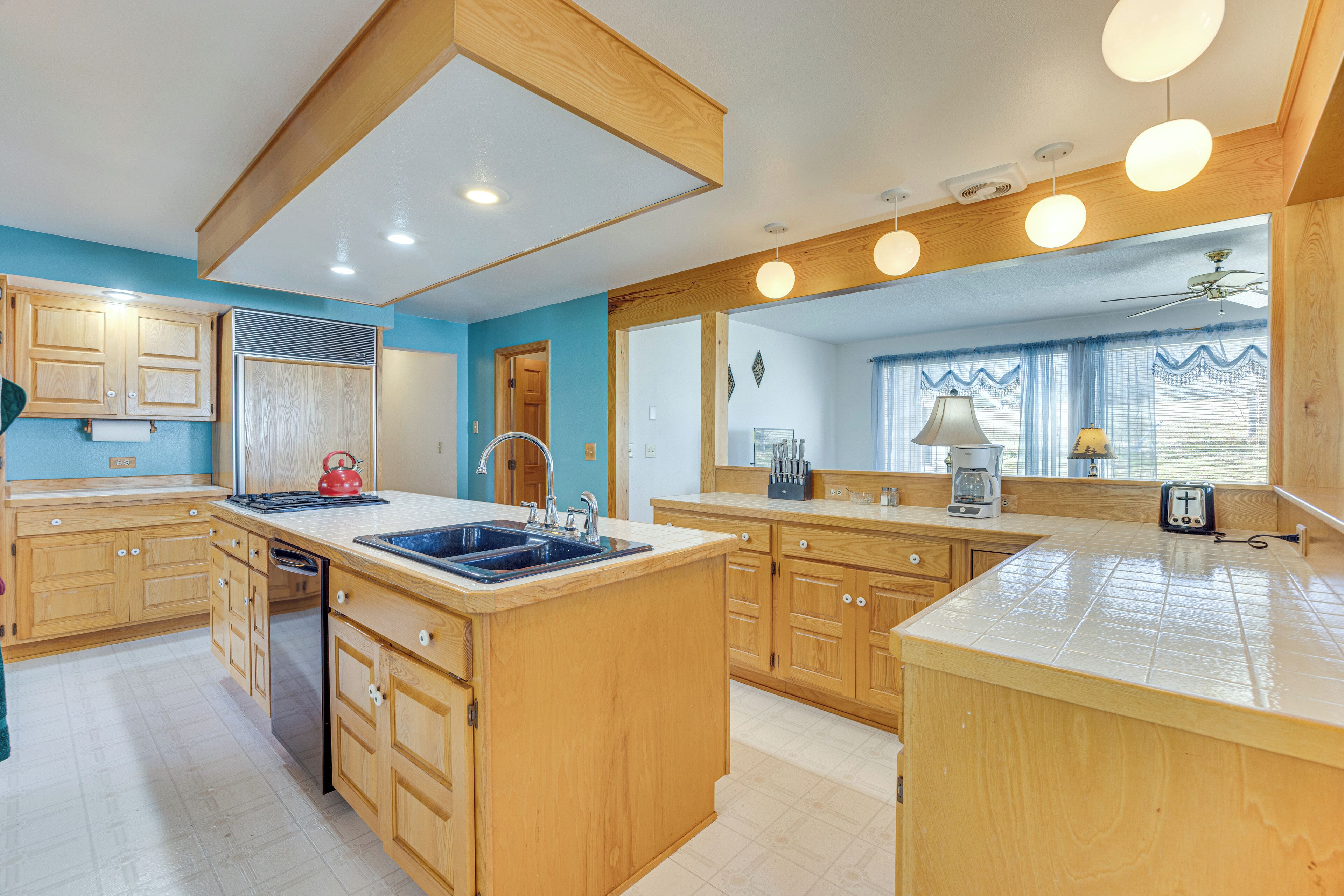 A spacious kitchen with wooden cabinets, a large island with a sink, and a ceiling fan.