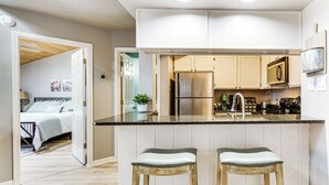 Una cucina moderna con isola centrale, sgabelli da bar e frigorifero.