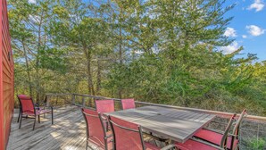 Eine Terrasse mit Tisch und Stühlen, umgeben von Bäumen.