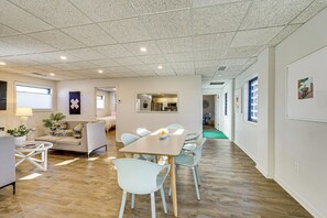 A spacious living area with a dining table, light-colored chairs, a sofa, and a coffee table.