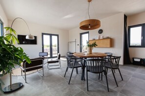 Een moderne eetruimte met een ronde tafel, zwarte stoelen en een hanglamp.