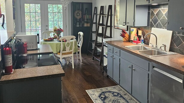Una cocina moderna con una isla central, armarios oscuros y una alfombra estampada.