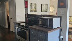 Una cocina moderna con horno empotrado, microondas y muebles oscuros.