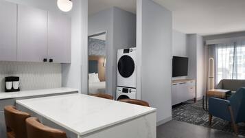 A modern kitchen with a central island, a washing machine, and a flat-screen TV.