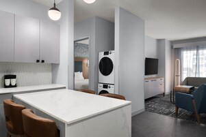 Una cocina moderna con una isla central, lavadora y televisor de pantalla plana.