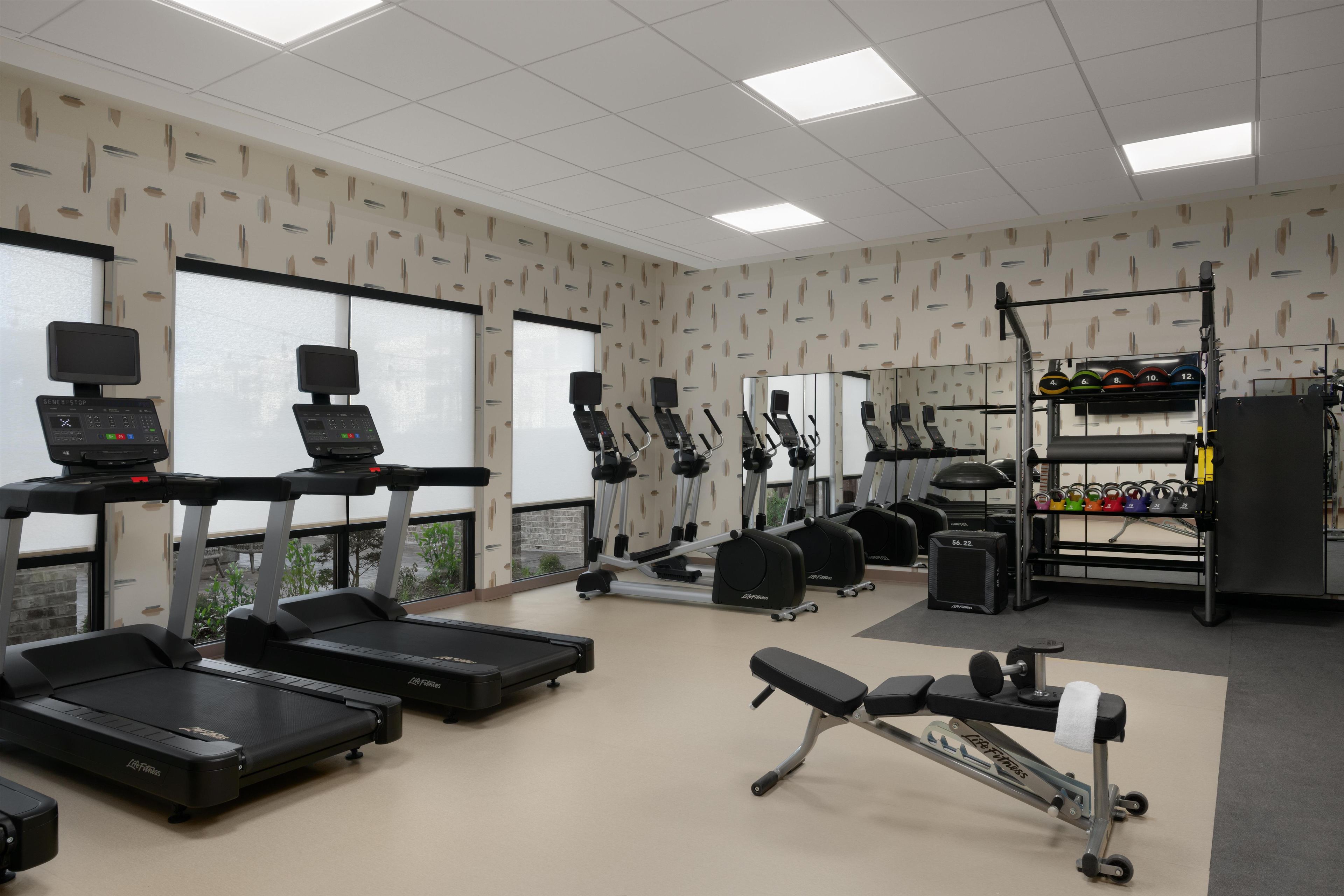 A gym with treadmills, elliptical machines, and weightlifting equipment.
