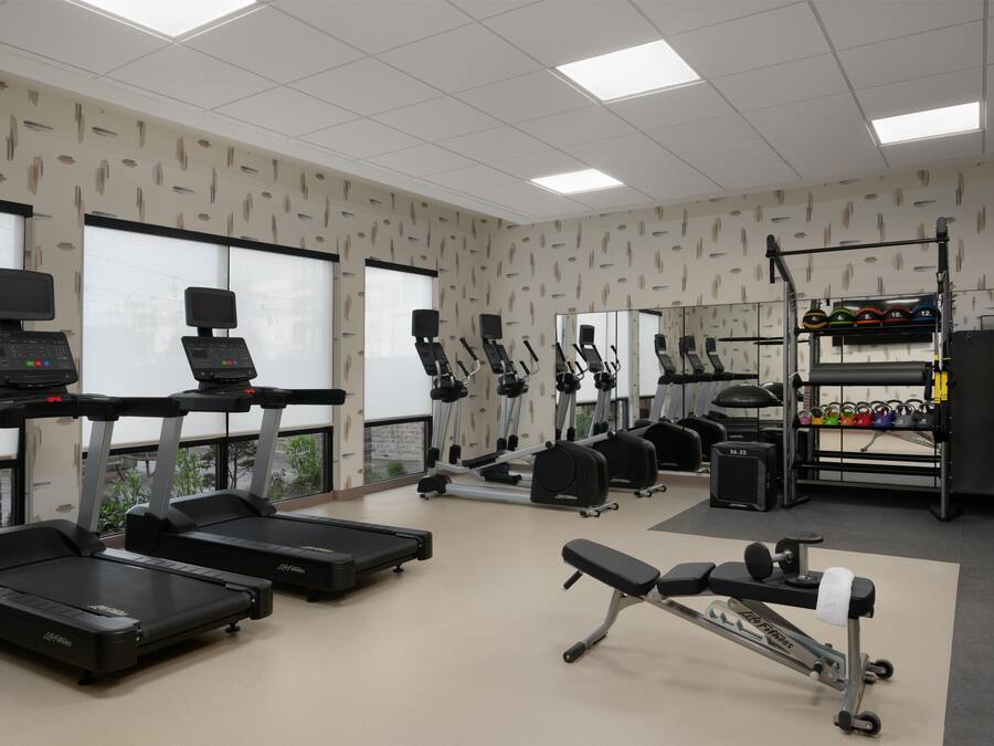 A gym with treadmills, elliptical machines, and weightlifting equipment.