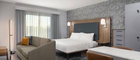 A hotel room with a bed, a sofa, a desk, and a wardrobe.