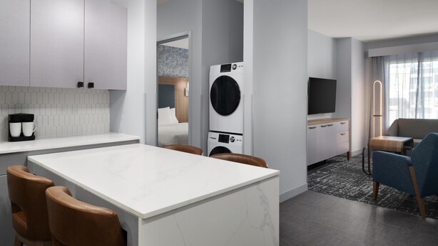 A modern kitchen with a central island, built-in appliances, and a dining area with chairs. - Homewood Suites By Hilton Covington, Ga (Covington)