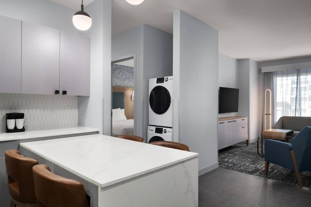 A modern kitchen with a central island, built-in appliances, and a dining area with chairs.