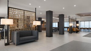 A modern lobby with a grey sofa, wooden partitions, and a reception desk. - Homewood Suites By Hilton Covington, Ga (Covington)