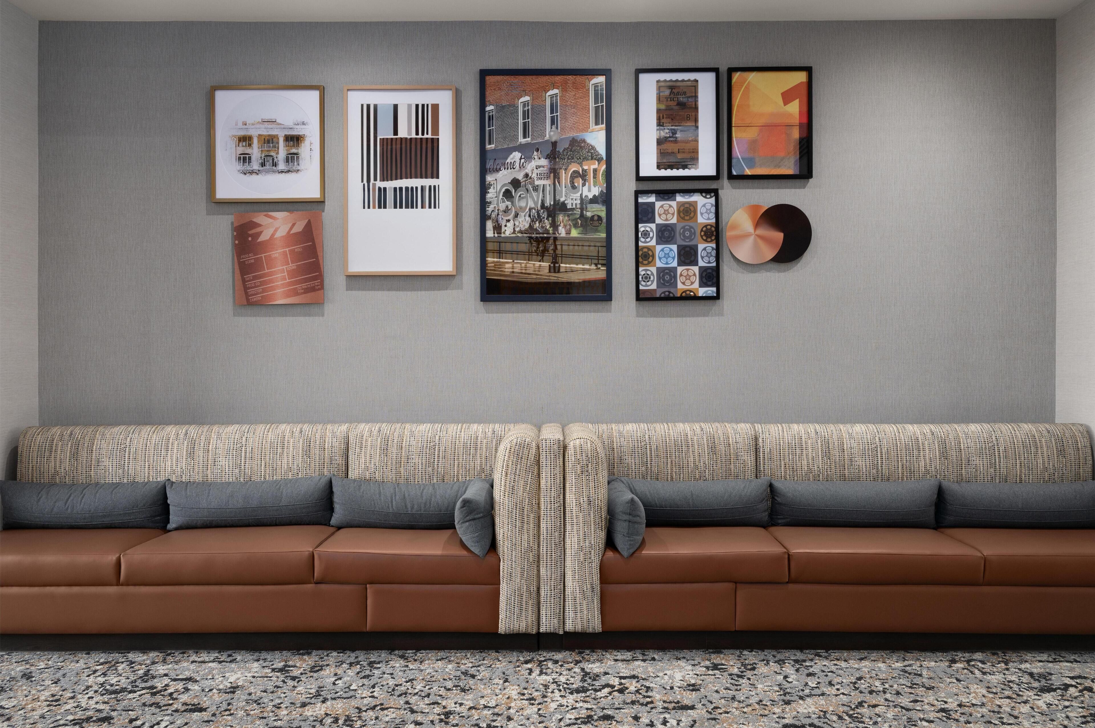 Ein modernes Wohnzimmer mit einem braunen Ledersofa, einem gemusterten Überwurf und einem Granitboden.