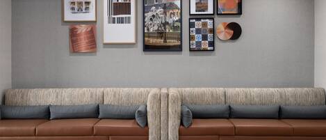 Ein modernes Wohnzimmer mit einem braunen Ledersofa, einem gemusterten Überwurf und einem Granitboden.